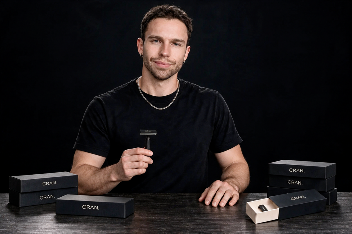 Anthony, founder of CRAN., holding the CRAN. razor behind a table of packaged boxes